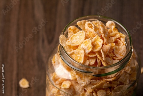 Glass jar filled with cereal flakes on a wooden surface photo