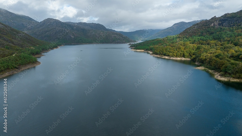 Scenic view of a wide river flowing amis the forest mountains on a gloomy weather