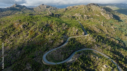 Aerial shot of a road stretching through the rocky forest mountain