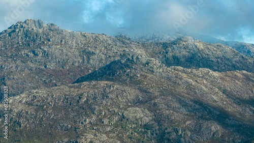 Aerial shot of rocky peaks of a mountain range under the cloudy sky © Jmb Pt/Wirestock Creators