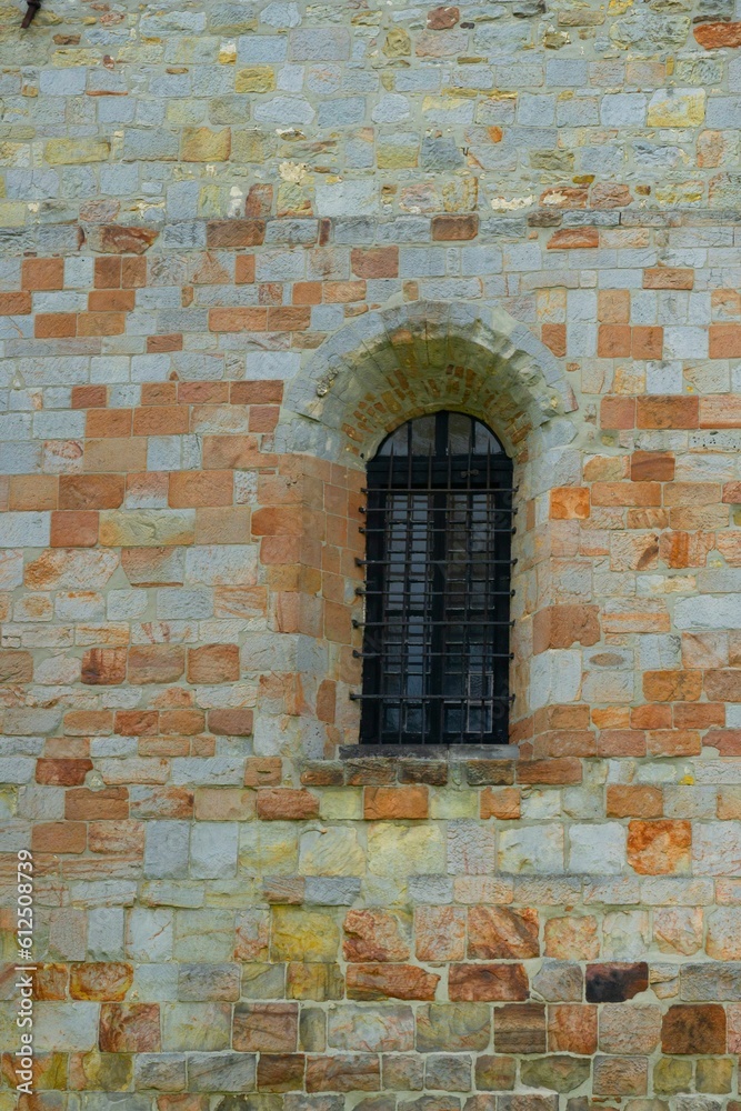 Vertical shot of a medieval-styled window on a stone wall
