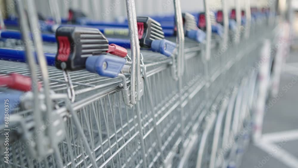 Rows of shopping carts on car park near entrance of supermarket