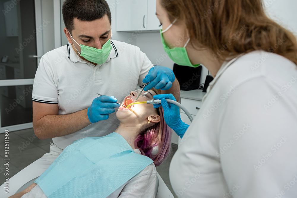 male dentist and a female assistant treat a patient. male dentist and a female assistant treat a patient.