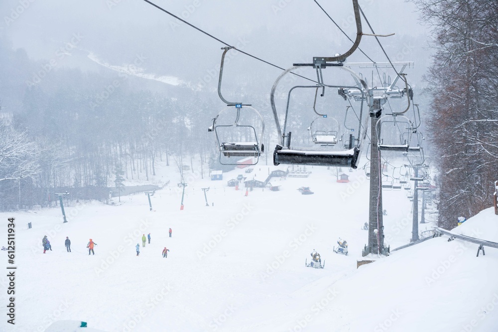 Low-angle of ropeway in winter with snowy landscape and people in the background Low-angle of ropeway in winter with snowy landscape and people in the background