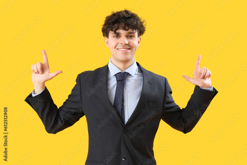 Young businessman showing loser gesture on yellow background Young businessman showing loser gesture on yellow background