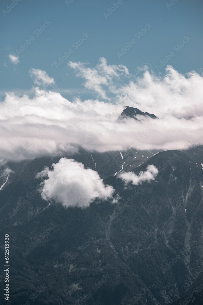 Scenic view of the mountain peaks touching the clouds under blue sky on a sunny day Scenic view of the mountain peaks touching the clouds under blue sky on a sunny day