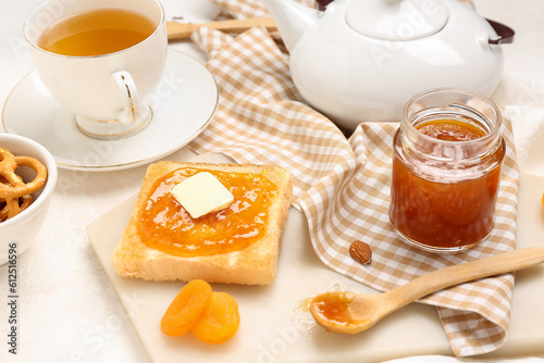 Tasty toast with apricot jam and cup of tea on light background