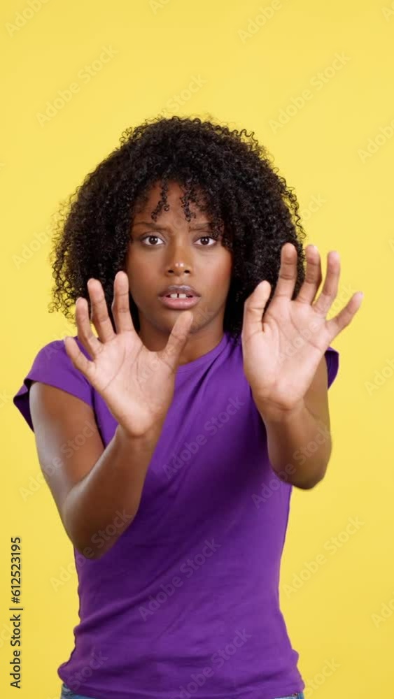 Woman with afro hair expressing fear while shielding with hands Woman with afro hair expressing fear while shielding with hands