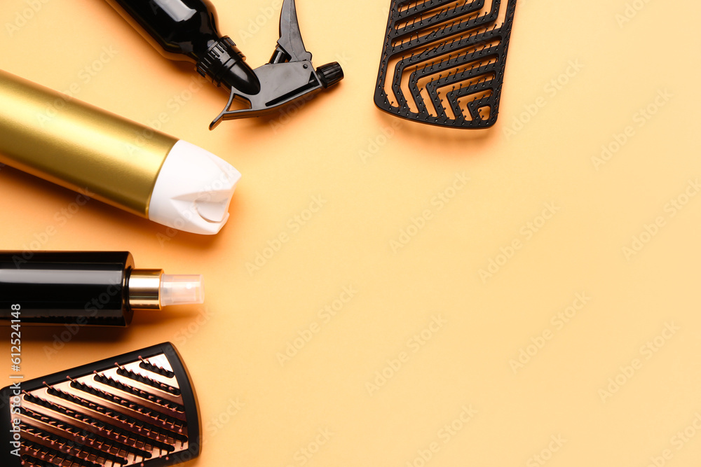 Frame made of hairdresser's brushes with sprays on color background