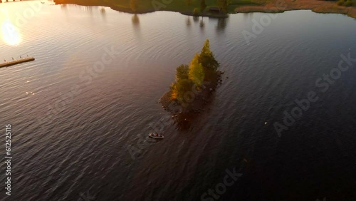 Drone footage of a small green-covered isle and a boat on a lake in Delsbo, Halsingland, Sweden photo