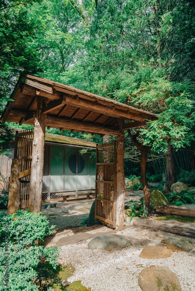 Vertical shot of an old wooden Japanese shrine surrounded by the green trees on a sunny day Vertical shot of an old wooden Japanese shrine surrounded by the green trees on a sunny day