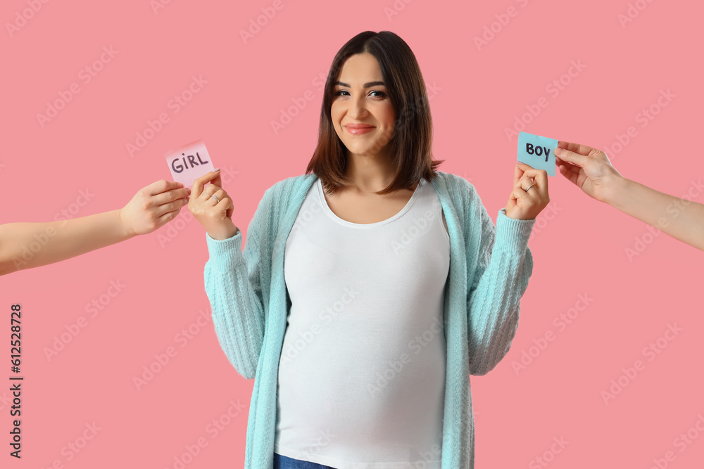 Young pregnant woman and female hands with sex of baby on pink background Young pregnant woman and female hands with sex of baby on pink background