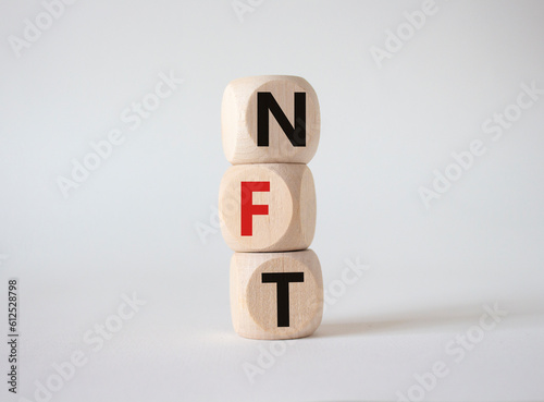 NFT - non-fungible token symbol. Concept word NFT on wooden cubes. Beautiful white background. Business and NFT concept. Copy space.
