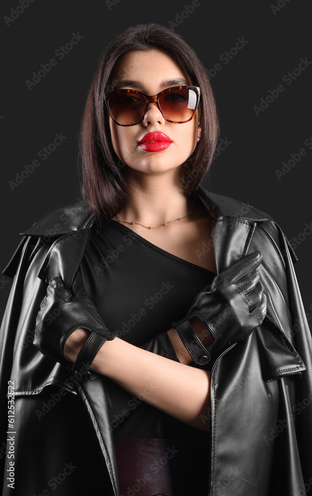Stylish young woman in sunglasses and leather gloves on dark background Stylish young woman in sunglasses and leather gloves on dark background