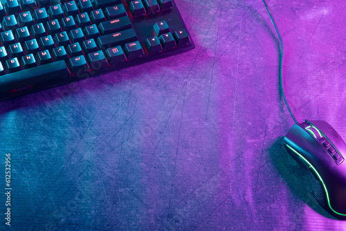 Top view with ample copy space of a gaming-themed desktop adorned with professional gaming accessories, illuminated by vibrant cyberpunk neon lights.