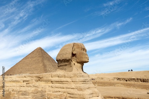 Ancient Egyptian pyramids and the Great Sphinx of Giza against a blue cloudy sky on a sunny day