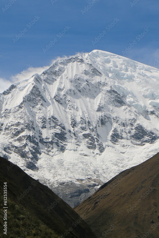 Vertical shot of the snow-covered peak of the mountain during the daytime