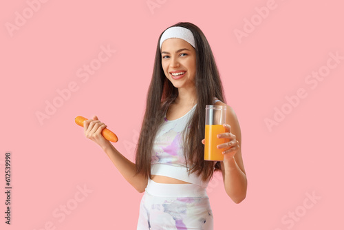 Smiling young woman holding fresh carrot and glass of orange juice, healthy l...
