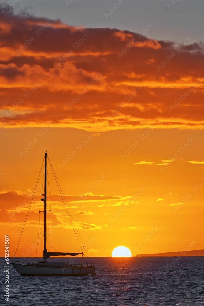 Vertical shot of a splendid sunset over the sea with a boat on the surface