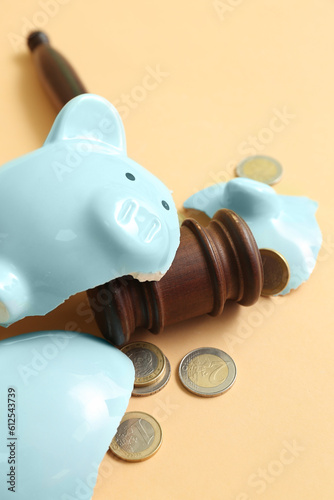 Broken piggy bank with judge gavel and money on orange background. Bankruptcy concept