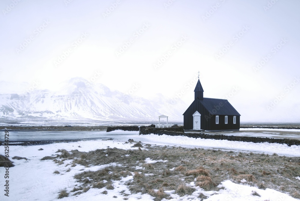 Distant shot of Budakirkja church in Iceland before a high mountain covered in snow