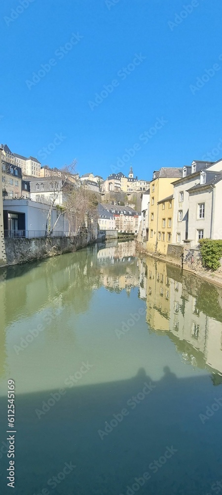 Vertical shot of the Alzette river between city buildings on a sunny day, in Luxembourg