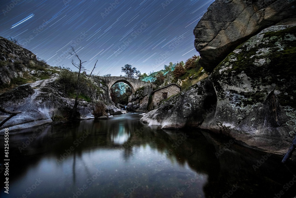 Long-exposure shot of stars above the river with a bridge