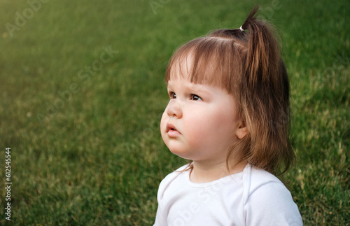 A little girl in the park is looking at the sunset. Portrait in profile. Lifestyle. Close-up. Copy space.