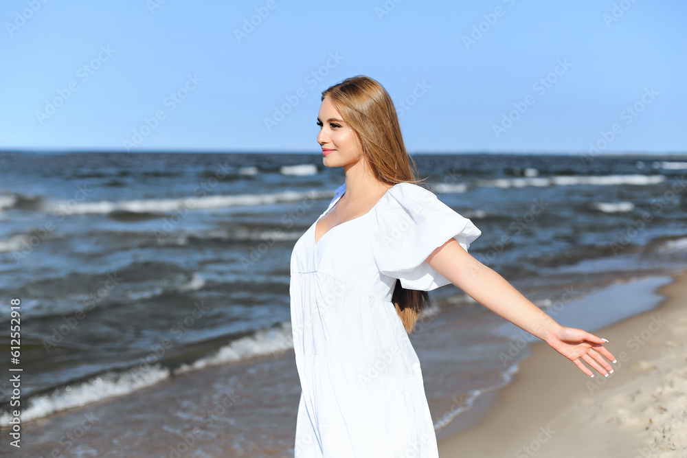 Happy smiling beautiful woman is on the ocean beach in a white summer dress, open arms. Happy smiling beautiful woman is on the ocean beach in a white summer dress, open arms.