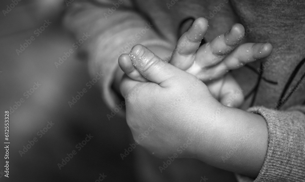 Grayscale shot of a child's hands on a blurred background Grayscale shot of a child's hands on a blurred background