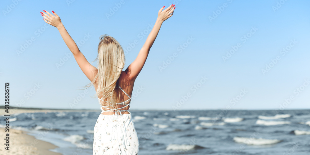 Happy blonde beautiful woman on the ocean beach standing in a white summer dress and glasses, raising hands. Happy blonde beautiful woman on the ocean beach standing in a white summer dress and glasses, raising hands.