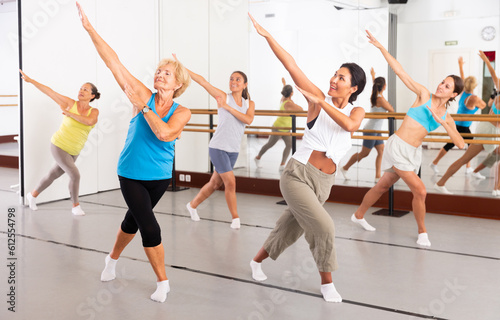 Active women engaged in dancing at a group training session in the studio practice modern energetic dance