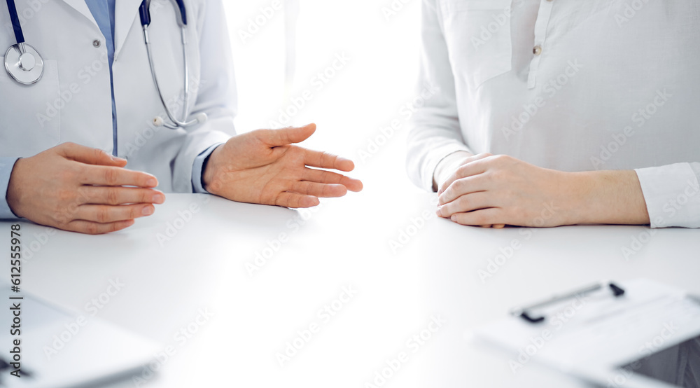 Doctor and patient discussing current health questions while sitting near of each other at the table in clinic, just hands closeup. Medicine concept. Doctor and patient discussing current health questions while sitting near of each other at the table in clinic, just hands closeup. Medicine concept.