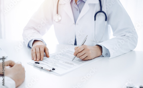 Doctor and patient discussing current health questions while sitting opposite of each other at the table in clinic, just hands closeup. Medicine concept.