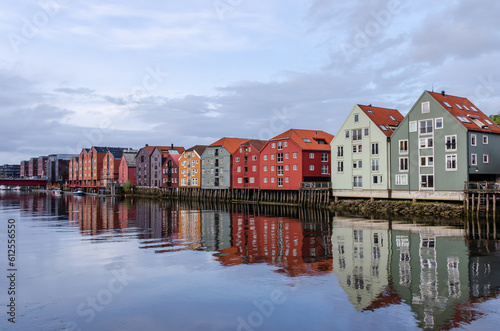 A row of typical colourful Norwegian houses built on pillars on top of a water surface. Reflecting on the water surface. © Jan