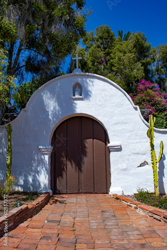 Beautiful White Adobe Arch with Dark Wooden Doors Is Framed by Southwestern Landscaping at the Mission Basilica San Diego de Alcala in San Diego, California, USA