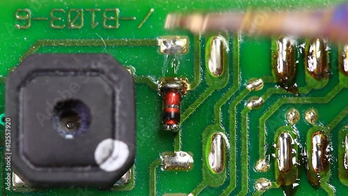 Engineer desolders and removes a surface mounted germanium diode. Technician desoldering using a soldering iron on the printed circuit board for remove part components. Static Macro Shot
