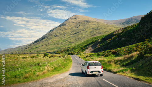 Beautiful landscape scenery with white car driving on empty scenic road trough nature and mountains at Delphi, county Mayo, Ireland 