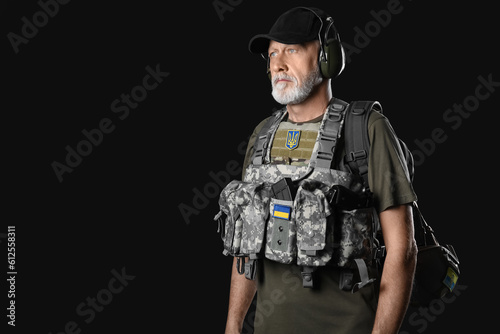 Ukrainian soldier with bag on dark background © Pixel-Shot