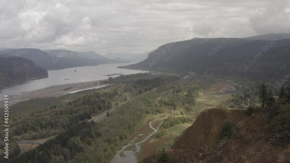 Aerial view of lakeshore with greenery and hills under cloudy sky on a gloomy day Aerial view of lakeshore with greenery and hills under cloudy sky on a gloomy day