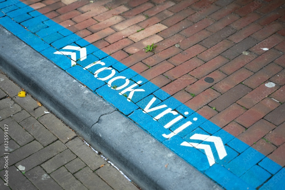 High-angle view of a blue sign with white writing found on the ground 
Translation: Smoke-Free