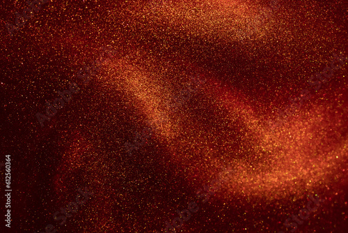 Amazing golden particles in red fluid. The shimmering overflow of gold particles in the red liquid. Beautiful shiny background.