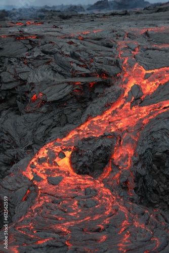 Volcanic eruption with glowing orange lava flow surrounded by a pool of bubbling magma
