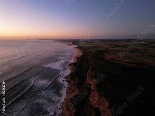 Aerial view of sea waves breaking beach during sunset