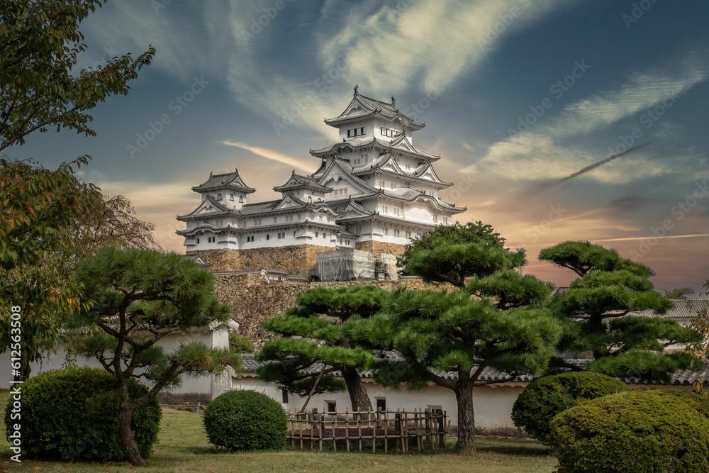 Low-angle of a hilltop Japanese castle complex in the city of Himeji, Japan, surrounded by trees