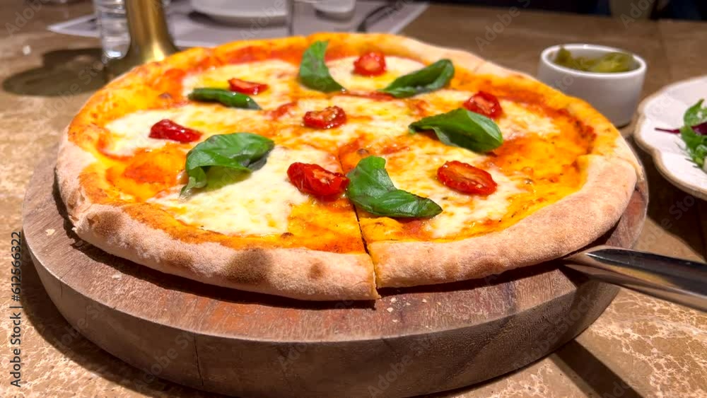 Closeup of authentic Italian stone-baked pizza with mozzarella and fresh basil on wooden board Closeup of authentic Italian stone-baked pizza with mozzarella and fresh basil on wooden board