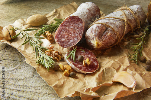 Italian salami wih sea salt, rosemary, garlic and nuts on paper. Rustic style. Close up.