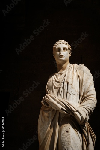 Vertical shot of a statue of Greek God against a black background.