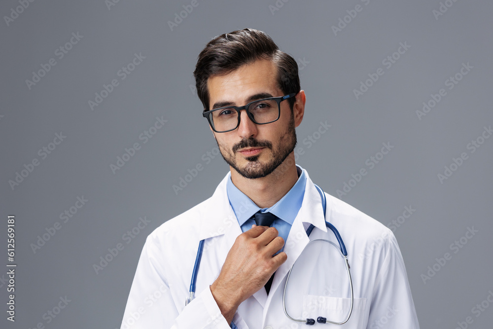 Male doctor in a white coat and glasses for vision and a stethoscope looks at the camera smile with teeth dentist on a gray isolated background, copy space, space for text, health