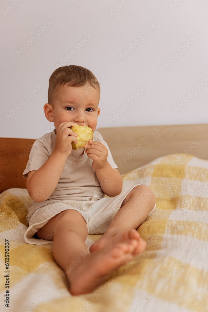 child eating apple while sitting on bed 